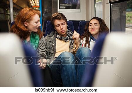 Three young friends travelling on train listening to music View Large Photo Image Stock Image - Three young friends travelling on train listening to music. Fotosearch