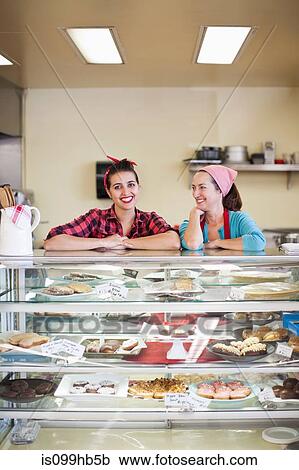 Stock Image - Two women standing at counter of bakery. Fotosearch