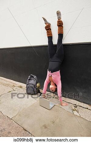 Woman performing handstand and using laptop on pavement View Large Photo Image Stock Image - Woman performing handstand and using laptop on pavement. Fotosearch