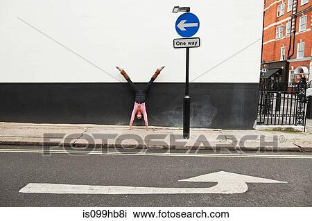 Woman performing handstand on pavement View Large Photo Image Stock Image - Woman performing handstand on pavement. Fotosearch