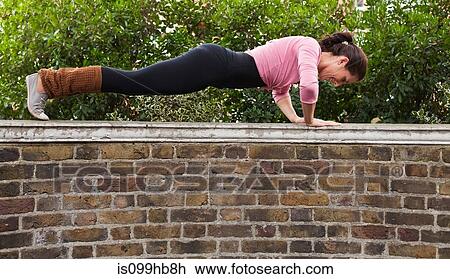 Woman performing push ups on top of wall View Large Photo Image Stock Image - Woman performing push ups on top of wall. Fotosearch