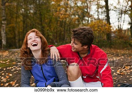 Stock Photo - Young couple in sportswear laughing in forest. Fotosearch