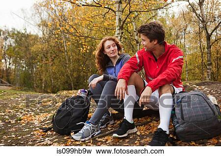 Stock Photo - Young couple in sportswear sitting in forest. Fotosearch