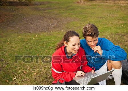 Young couple using laptop in park View Large Photo Image Stock Image - Young couple using laptop in park. Fotosearch