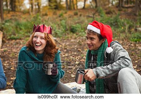 Stock Image - Young couple wearing Santa hats and crowns in forest. Fotosearch