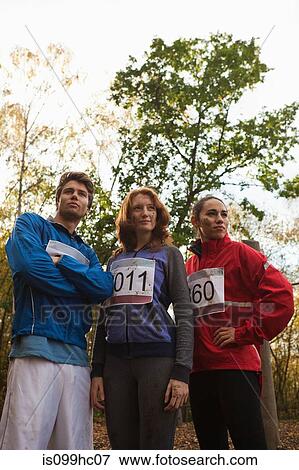 Stock Photo - Young friends in sportswear standing together in forest. Fotosearch