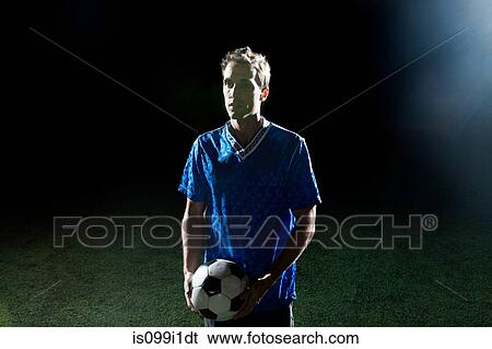 Young man holding soccer ball on pitch View Large Photo Image Stock Photograph - Young man holding soccer ball on pitch. Fotosearch