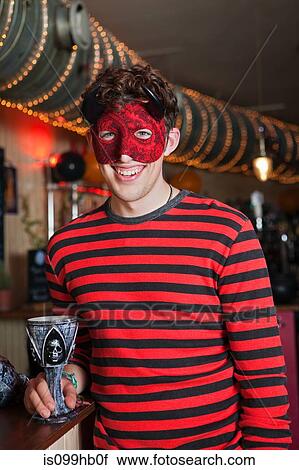 Young man in costume and mask in bar, portrait View Large Photo Image Stock Image - Young man in costume and mask in bar, portrait. Fotosearch