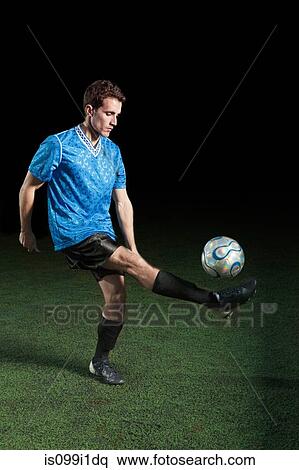 Young man kicking soccer ball on pitch View Large Photo Image Stock Photography - Young man kicking soccer ball on pitch. Fotosearch