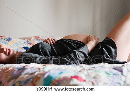 Young pregnant woman lying on bed View Large Photo Image Stock Image - Young pregnant woman lying on bed. Fotosearch