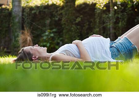 Young pregnant woman lying on grass View Large Photo Image Stock Image - Young pregnant woman lying on grass. Fotosearch