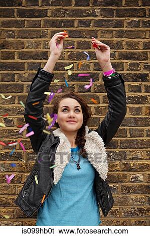 Young woman dropping colourful confetti against brick wall View Large Photo Image Stock Photograph - Young woman dropping colourful confetti against brick wall. Fotosearch