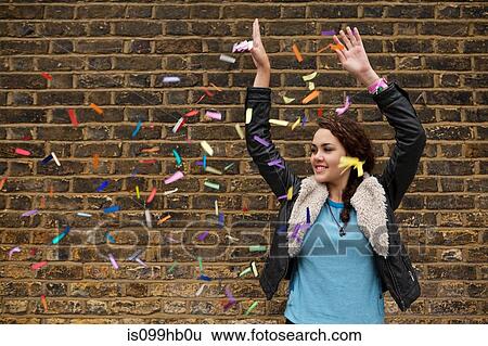 Young woman dropping colourful confetti against brick wall View Large Photo Image Stock Photograph - Young woman dropping colourful confetti against brick wall. Fotosearch