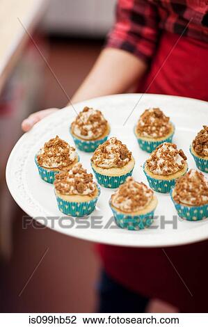 Young woman holding plate of freshly baked cakes in bakery View Large Photo Image Stock Image - Young woman holding plate of freshly baked cakes in bakery. Fotosearch