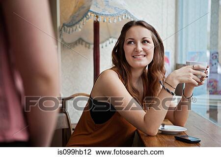 Young woman in cafe smiling at friend View Large Photo Image Stock Image - Young woman in cafe smiling at friend. Fotosearch
