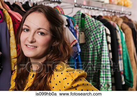 Stock Image - Young woman in clothes shop, portrait. Fotosearch