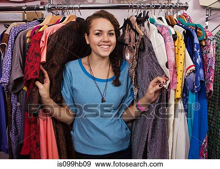 Stock Photo - Young woman in clothes shop, portrait. Fotosearch