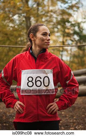 Stock Photo - Young woman in sportswear standing in forest. Fotosearch