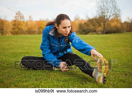 Young woman performing stretches in park View Large Photo Image Stock Photograph - Young woman performing stretches in park. Fotosearch