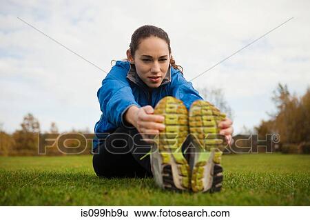 Young woman performing stretches in park View Large Photo Image Stock Photograph - Young woman performing stretches in park. Fotosearch