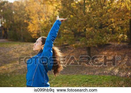 Young woman performing stretches in park View Large Photo Image Stock Photography - Young woman performing stretches in park. Fotosearch