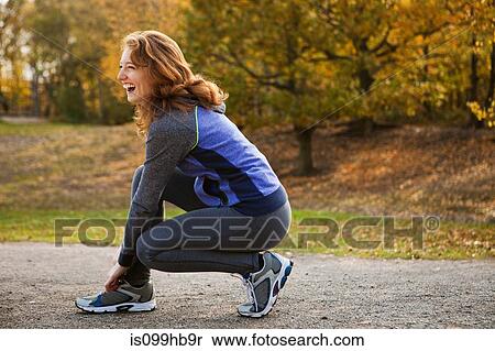 Stock Photography - Young woman performing stretches in park. Fotosearch