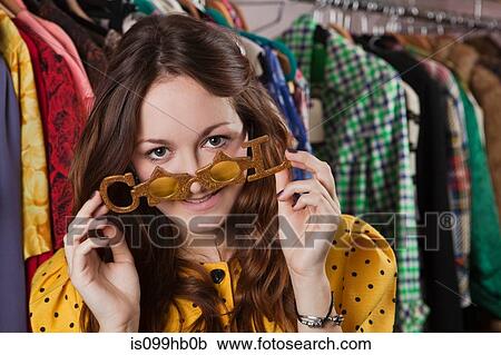 Young woman trying on novelty glasses in clothes shop, smiling View Large Photo Image Stock Image - Young woman trying on novelty glasses in clothes shop, smiling. Fotosearch