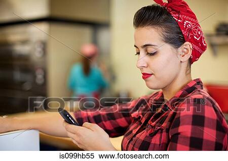 Young woman using cellphone in bakery View Large Photo Image Stock Photography - Young woman using cellphone in bakery. Fotosearch
