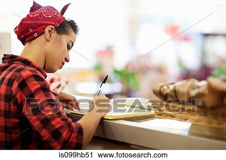 Young woman writing on counter of bakery View Large Photo Image Stock Image - Young woman writing on counter of bakery. Fotosearch