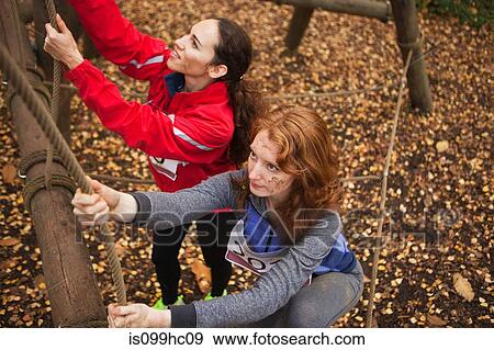 Stock Photo - Young women climbing rope on assualt course. Fotosearch