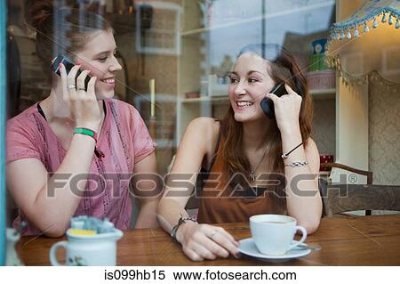 Young women in cafe on cell phones View Large Photo Image Stock Photography - Young women in cafe on cell phones. Fotosearch