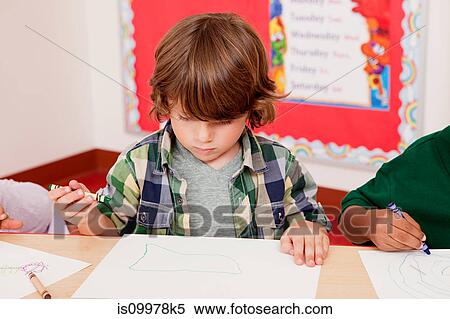 Boy drawing a picture in class View Large Photo Image Stock Photography - Boy drawing a picture in class. Fotosearch