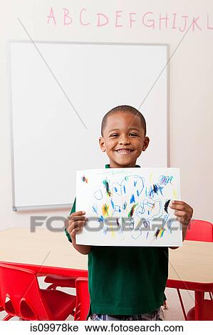Stock Image - Boy holding picture that he has drawn in school. Fotosearch