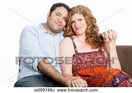 Picture - Couple relaxing on sofa against white background. Fotosearch