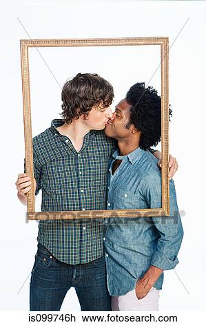 Stock Image - Gay couple kissing with picture frame against white background. Fotosearch