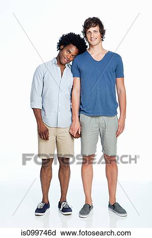 Stock Image - Gay couple standing against white background. Fotosearch
