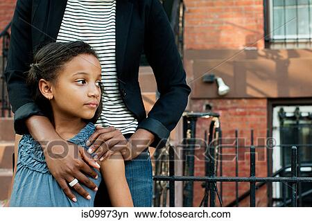 Girl standing with mother, looking away View Large Photo Image Picture - Girl standing with mother, looking away. Fotosearch