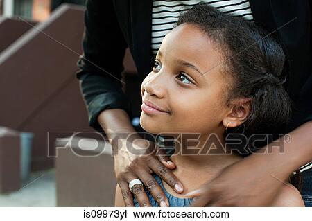 Stock Image - Girl standing with mother, looking away. Fotosearch