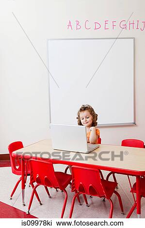 Stock Image - Girl using laptop in classroom. Fotosearch