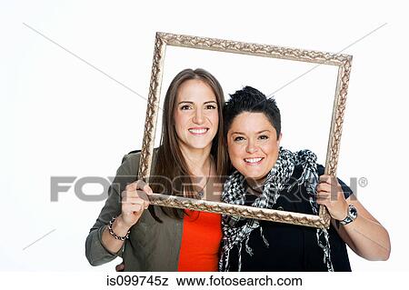 Lesbian couple holding picture frame against white background View Large Photo Image Stock Photo - Lesbian couple holding picture frame against white background. Fotosearch
