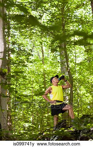 Stock Photo - Man drinking water in forest. Fotosearch