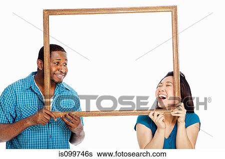 Mixed race couple holding picture frame against white background View Large Photo Image Stock Photograph - Mixed race couple holding picture frame against white background. Fotosearch