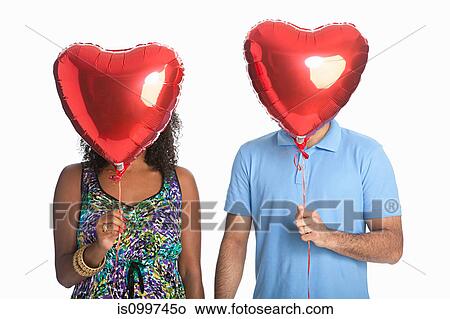 Mixed race couple holding red balloons against white background View Large Photo Image Picture - Mixed race couple holding red balloons against white background. Fotosearch