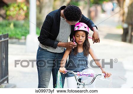 Mother adjusting daughter's bicycle helmet View Large Photo Image Stock Image - Mother adjusting daughter's bicycle helmet. Fotosearch