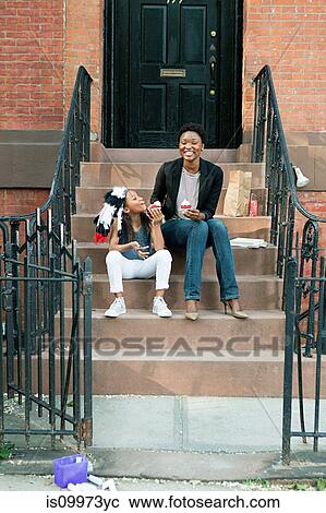Stock Image - Mother and daughter eating ice cream on steps. Fotosearch