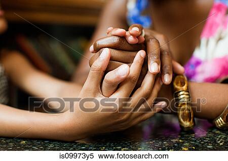 Stock Photography - Mother and daughter holding hands in cafe. Fotosearch