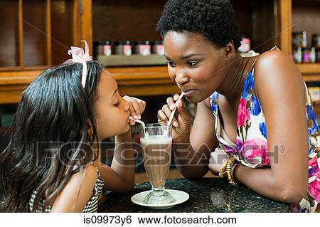Mother and daughter sharing milkshake in cafe View Large Photo Image Stock Photograph - Mother and daughter sharing milkshake in cafe. Fotosearch