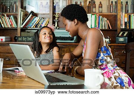 Stock Photography - Mother and daughter using laptop at home. Fotosearch