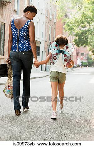 Mother and daughter walking along street, rear view View Large Photo Image Stock Image - Mother and daughter walking along street, rear view. Fotosearch