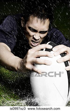 Rugby player with ball in the rain View Large Photo Image Stock Image - Rugby player with ball in the rain. Fotosearch